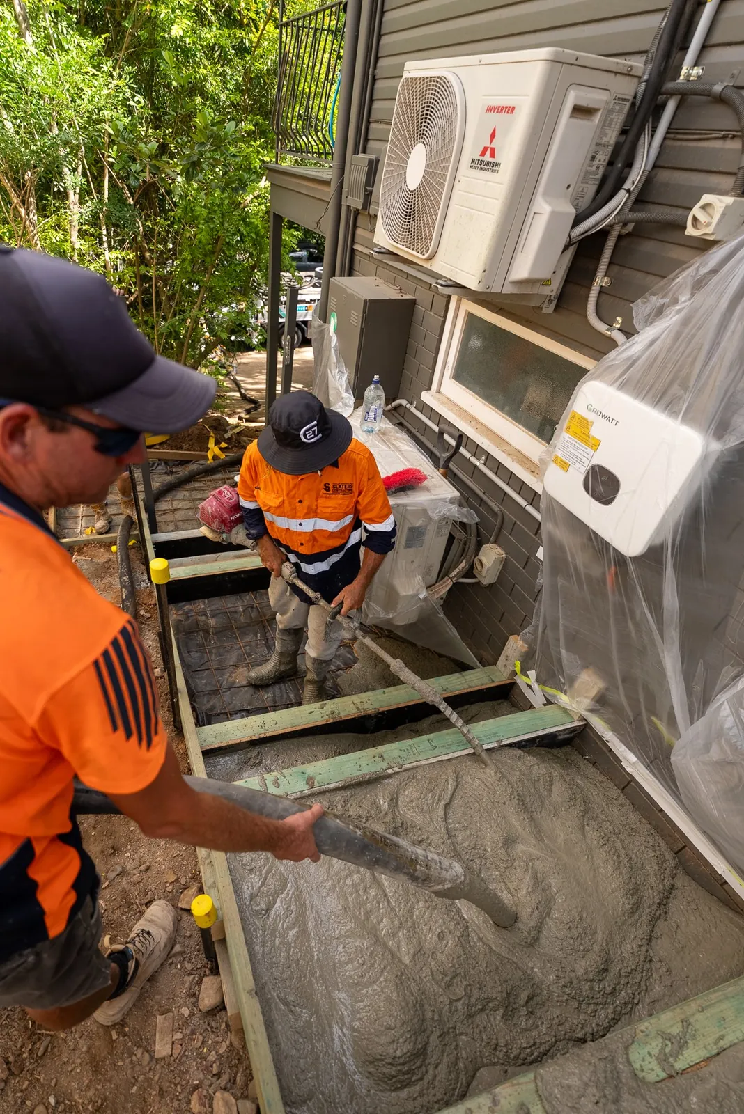 Screeding a fresh concrete pour down the side of a house