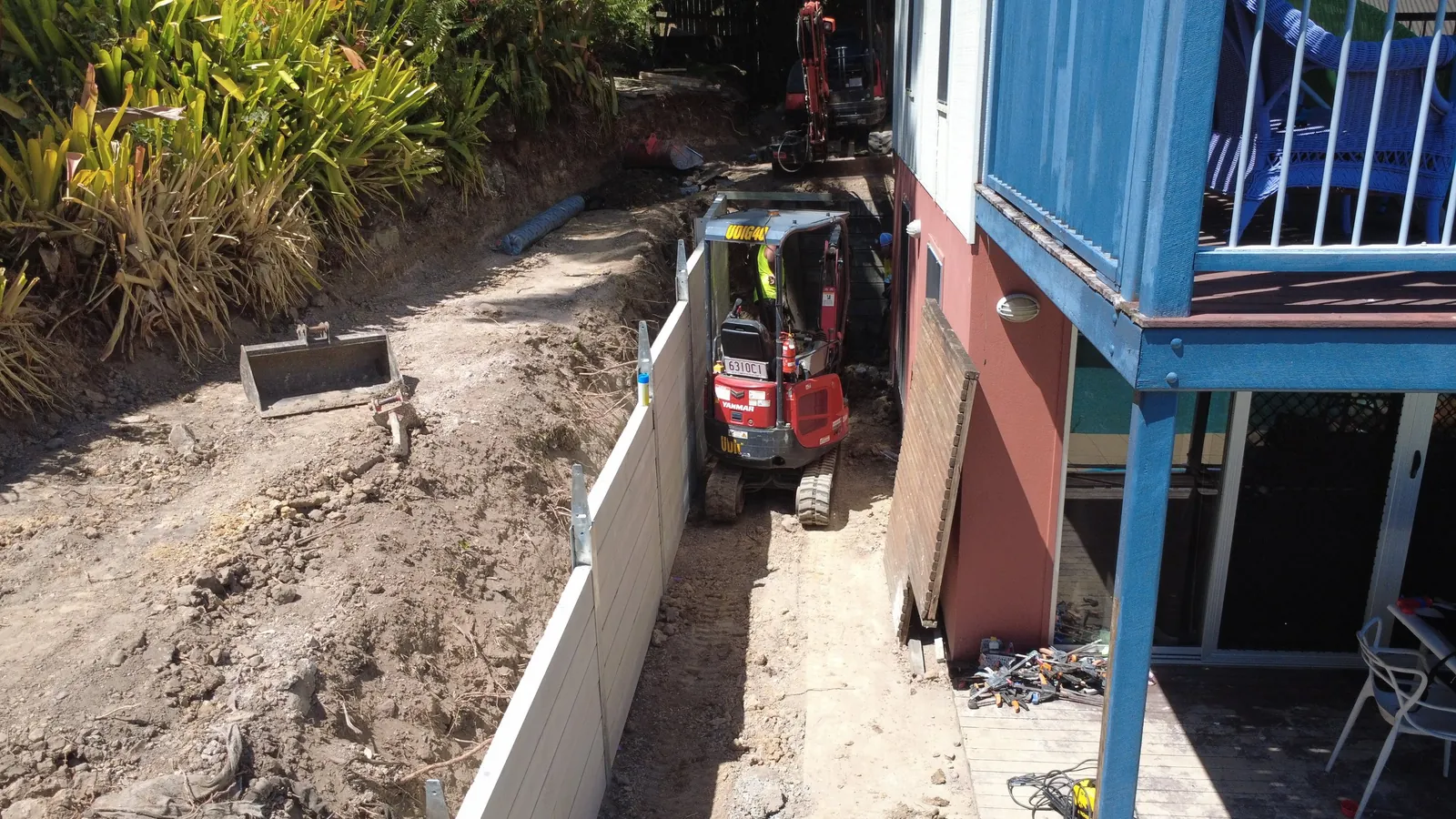 Drone view of tight access digging down the side of a house