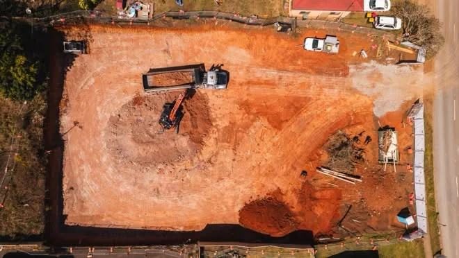 Drone view of a whole block cut out, with an excavator loading a truck