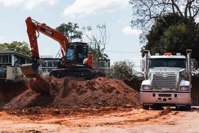 Excavator on a spoil pile with a Mack truck waiting to load