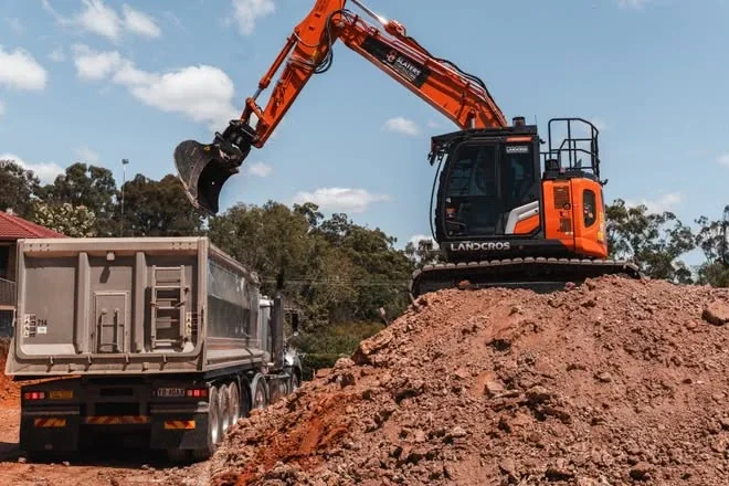 Excavator on a spoil pile loading a truck and dog trailer