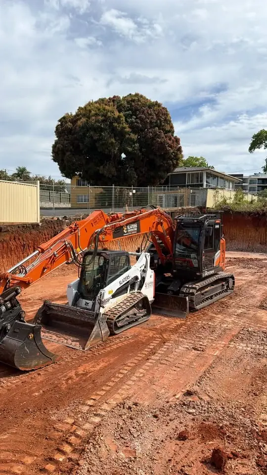 Excavator and posi track parked on a deep site cut