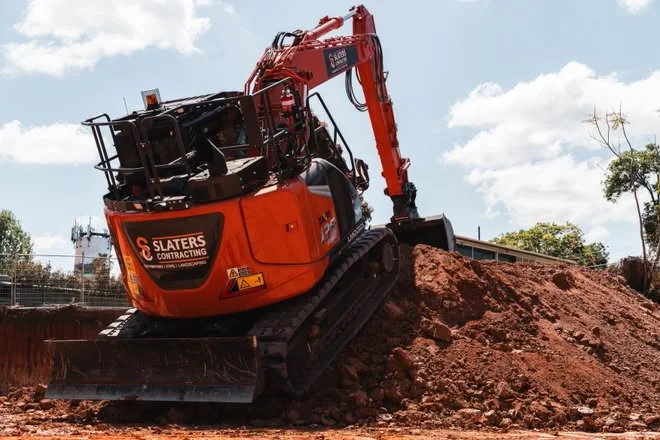 Slaters excavator climbing a red-dirt spoil pile