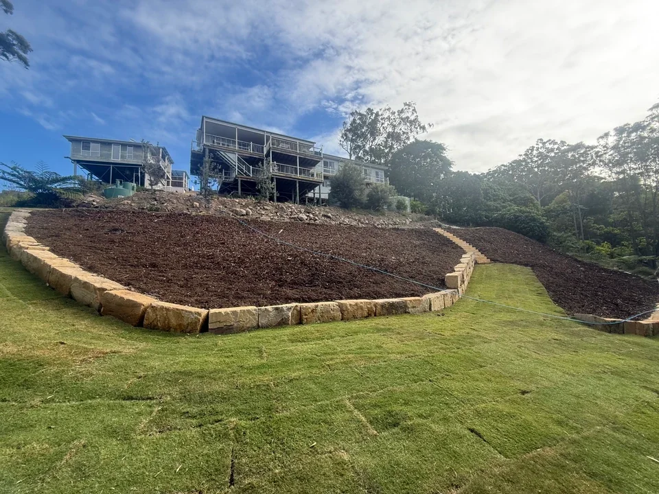 Sandstone edging and fresh turf on a sloping block below hillside homes