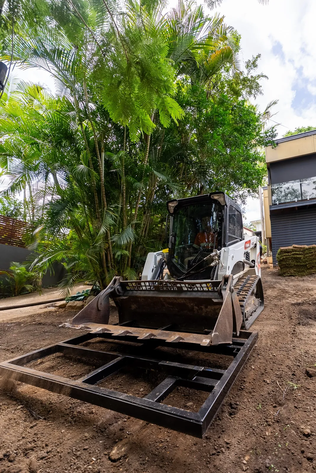 Posi track with pallet forks working under palm trees