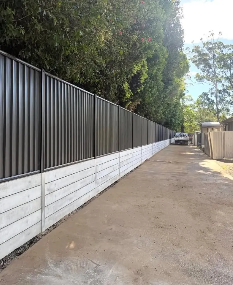 Concrete sleeper wall with a dark Colorbond fence along a driveway