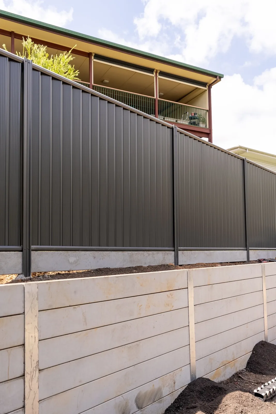 New concrete sleeper wall with a dark Colorbond fence on top