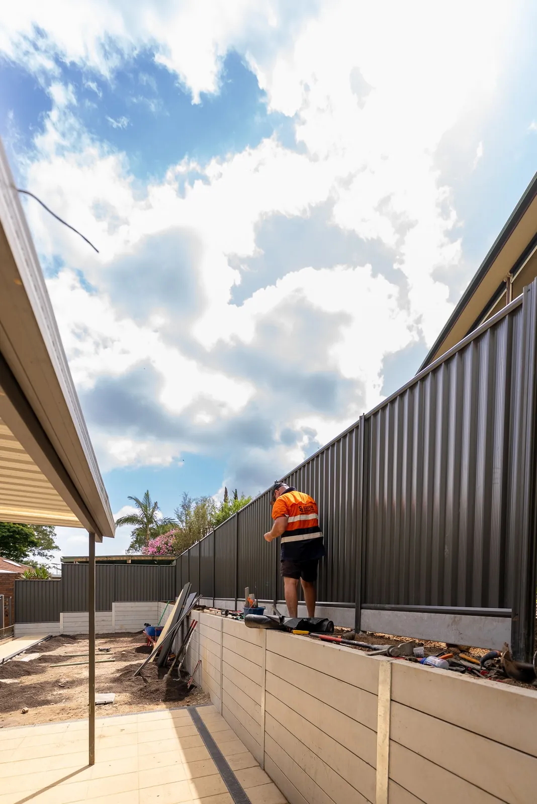 A long sleeper retaining wall and fence down the side of a home